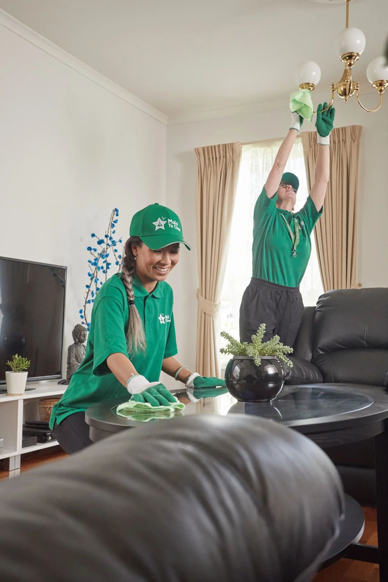 Maid to Clean cleaners dusting a light fitting and polishing a table in a living room